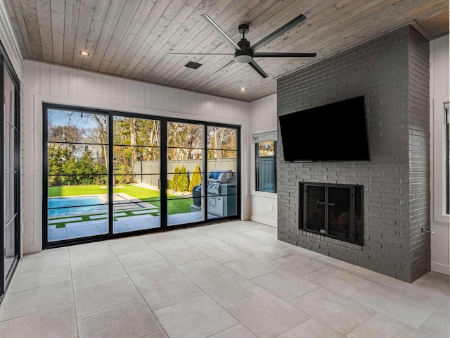 unfurnished living room with wooden ceiling, light tile patterned floors, a fireplace, and ceiling fan