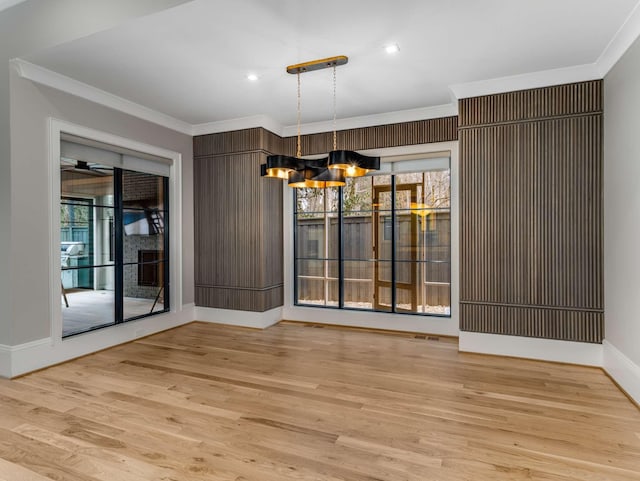 unfurnished dining area with light wood finished floors, recessed lighting, an inviting chandelier, ornamental molding, and baseboards