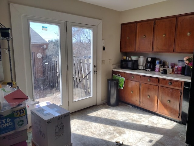 kitchen featuring brown cabinetry, black microwave, and light countertops