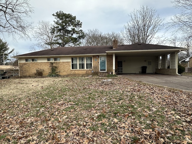 single story home with an attached carport, brick siding, driveway, and a chimney