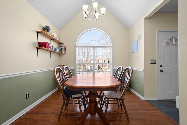 dining space with lofted ceiling, a notable chandelier, dark wood finished floors, and baseboards