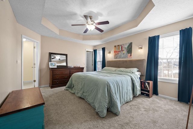 bedroom featuring baseboards, a tray ceiling, and light colored carpet