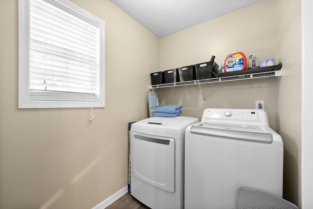 clothes washing area with laundry area, baseboards, separate washer and dryer, and a textured ceiling