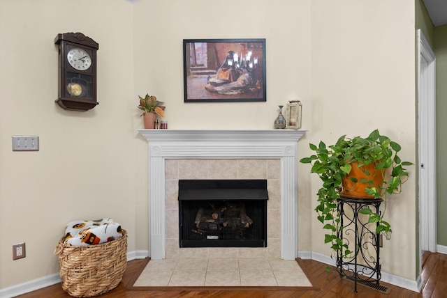 details with baseboards, a tiled fireplace, and wood finished floors