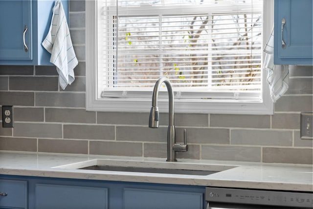 kitchen featuring blue cabinets, dishwasher, decorative backsplash, and a sink