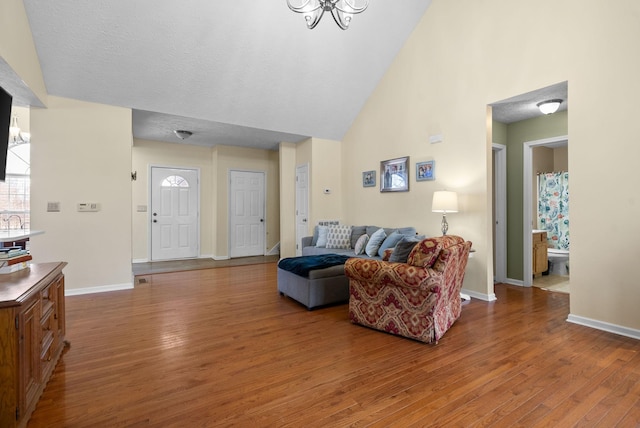 living area featuring a high ceiling, wood finished floors, and baseboards