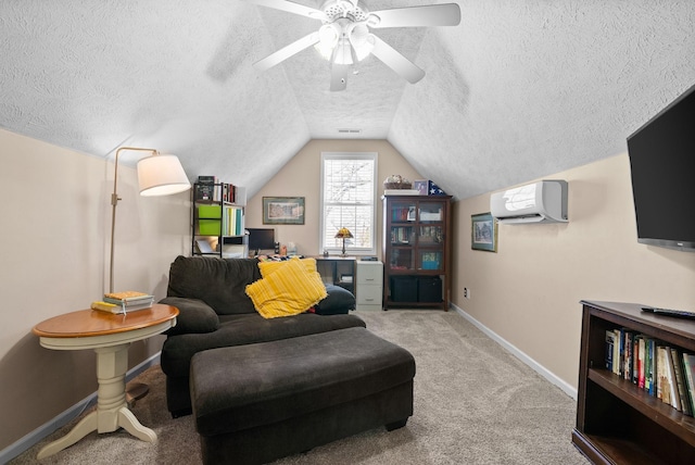 sitting room featuring a textured ceiling, a wall unit AC, light colored carpet, baseboards, and vaulted ceiling