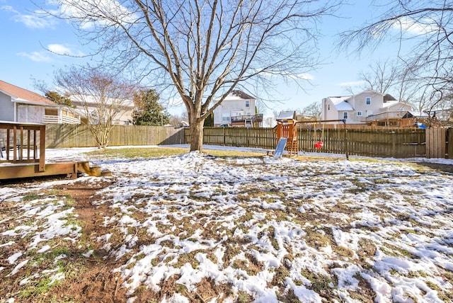 yard layered in snow featuring a playground, a fenced backyard, and a residential view