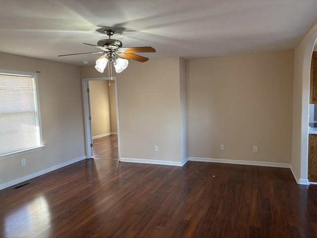 unfurnished room featuring a ceiling fan, dark wood-style flooring, visible vents, and baseboards