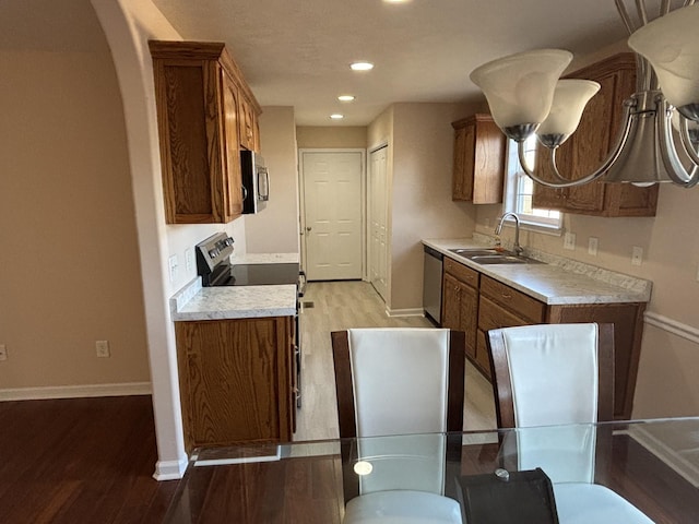 kitchen featuring brown cabinets, light wood-style floors, stainless steel appliances, and a sink