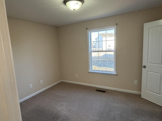 spare room with carpet flooring, visible vents, and baseboards