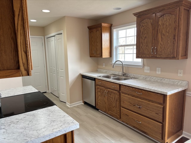 kitchen with light countertops, stainless steel dishwasher, a sink, and baseboards