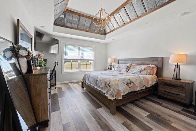 bedroom featuring baseboards, a notable chandelier, a tray ceiling, and hardwood / wood-style floors