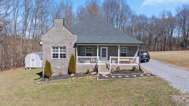 view of front facade featuring a chimney, a storage unit, a porch, a front yard, and an outdoor structure