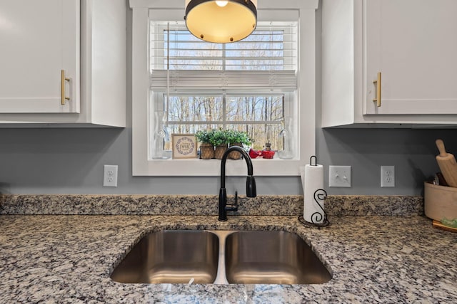 room details featuring stone countertops, white cabinets, and a sink