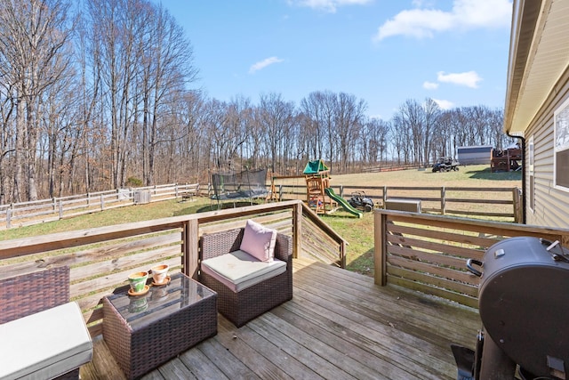 deck with a trampoline, a playground, a grill, and a fenced backyard