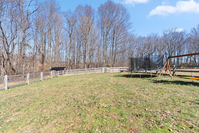 view of yard featuring a trampoline and fence