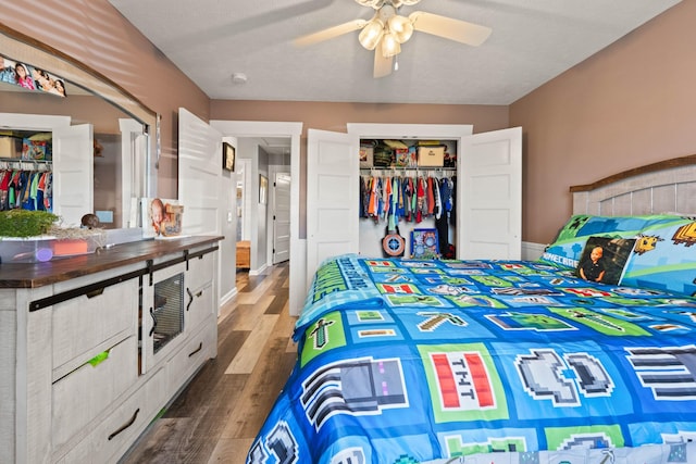 bedroom with a closet, ceiling fan, baseboards, and wood finished floors