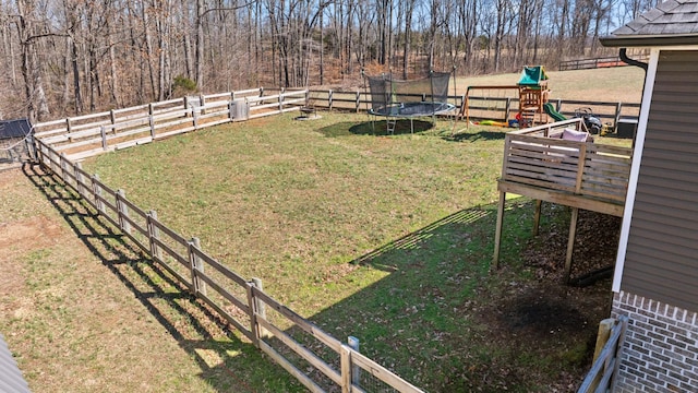 view of yard with a trampoline, fence, and a playground