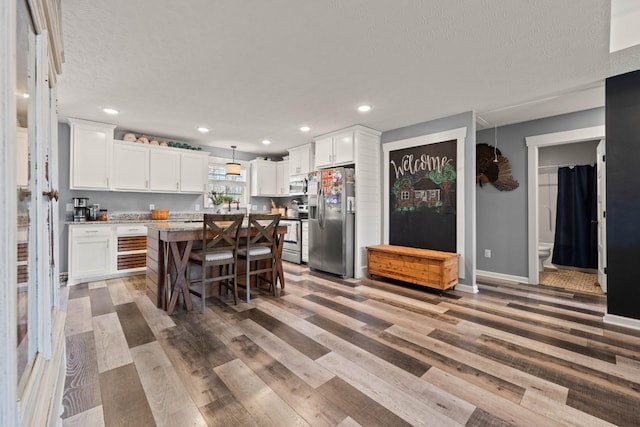 kitchen with appliances with stainless steel finishes, white cabinetry, a kitchen island, and a kitchen breakfast bar