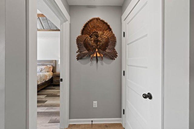 corridor featuring light wood finished floors and baseboards