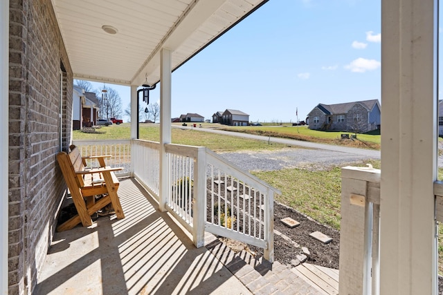 exterior space with a porch, a residential view, and a lawn