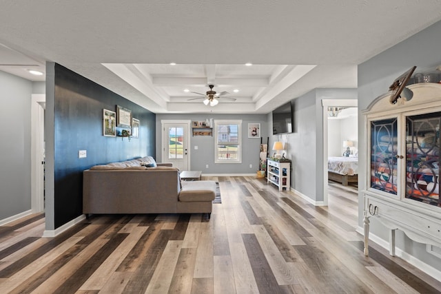 living area with ceiling fan, recessed lighting, wood finished floors, baseboards, and a tray ceiling