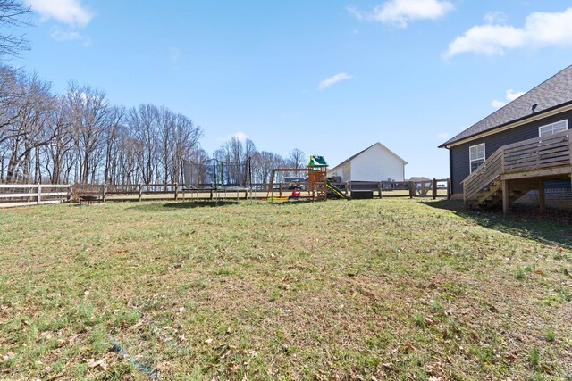 view of yard with a trampoline, a playground, and fence