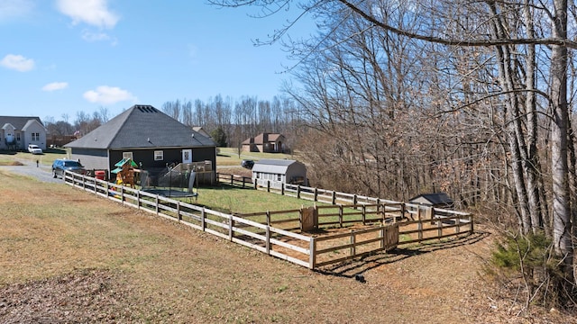 view of yard with a rural view, fence, an outdoor structure, and a storage unit