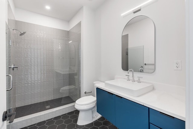 bathroom featuring toilet, tile patterned floors, a tile shower, and vanity