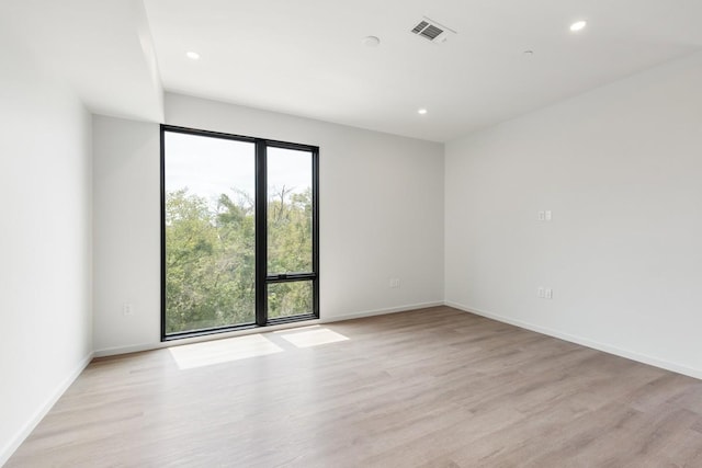 empty room featuring light wood finished floors, baseboards, visible vents, and recessed lighting