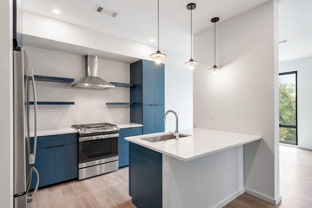 kitchen with appliances with stainless steel finishes, a peninsula, light countertops, wall chimney range hood, and open shelves