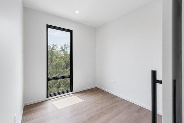 empty room with light wood finished floors, recessed lighting, and baseboards