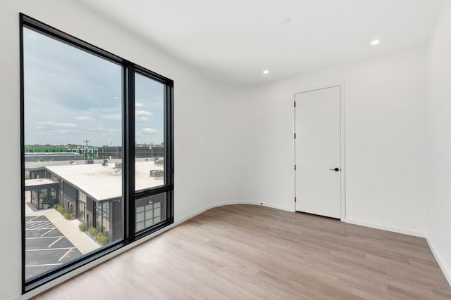 spare room featuring recessed lighting, baseboards, and light wood finished floors