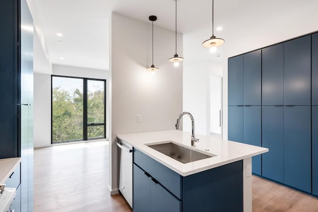 kitchen featuring modern cabinets, decorative light fixtures, light countertops, blue cabinetry, and a sink