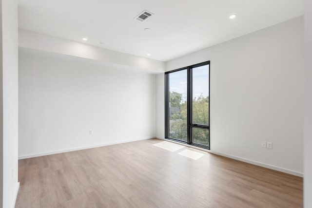 empty room with light wood finished floors, recessed lighting, visible vents, and baseboards