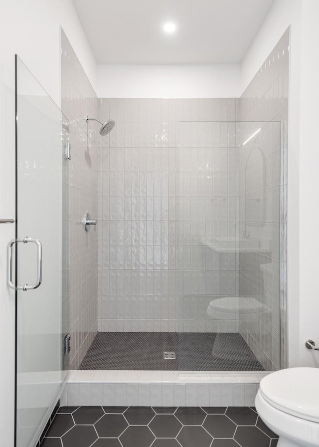 bathroom with a shower stall, toilet, and tile patterned floors