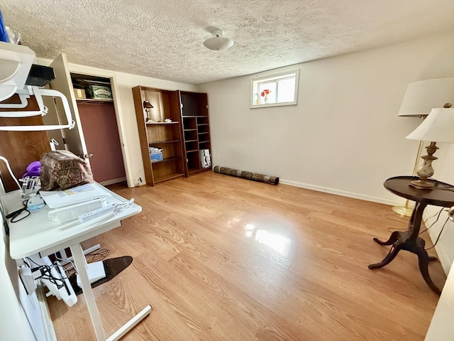 unfurnished office with a textured ceiling, baseboards, and wood finished floors