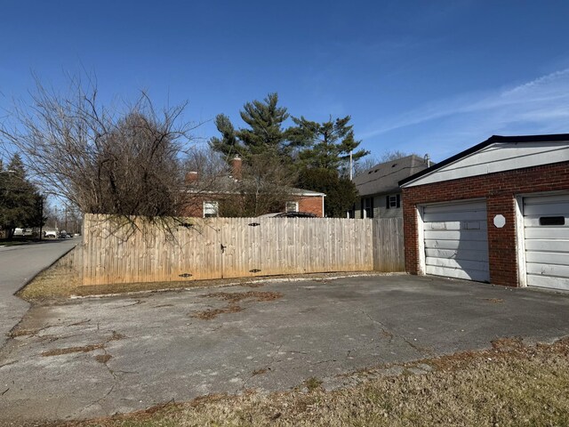 view of home's exterior with a garage, brick siding, and fence