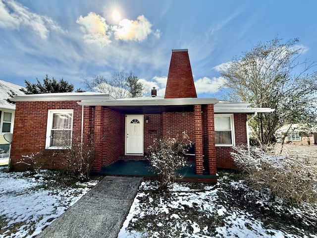 view of front of house with brick siding and a chimney