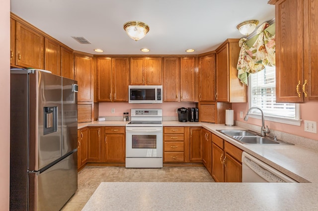 kitchen with light countertops, white appliances, and a sink