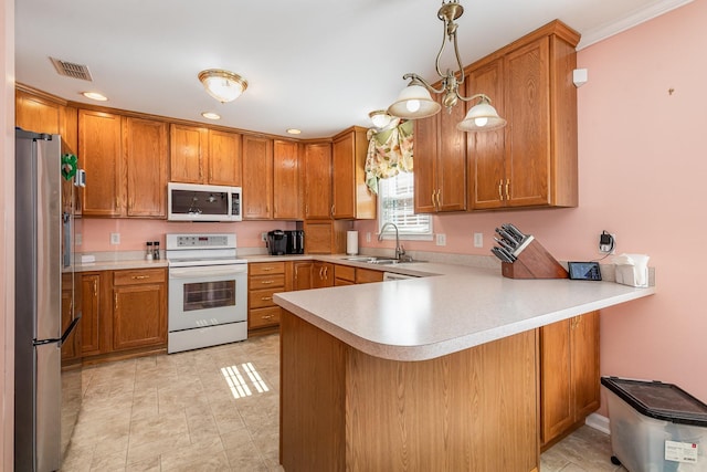 kitchen featuring light countertops, hanging light fixtures, a sink, white appliances, and a peninsula