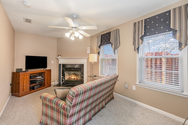 living area with light carpet, baseboards, visible vents, ceiling fan, and a fireplace