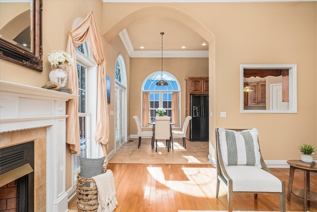 living area featuring baseboards, a high end fireplace, crown molding, light wood-style floors, and recessed lighting