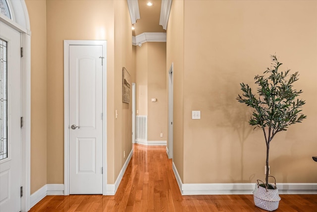 hall featuring light wood-style floors, baseboards, and ornamental molding