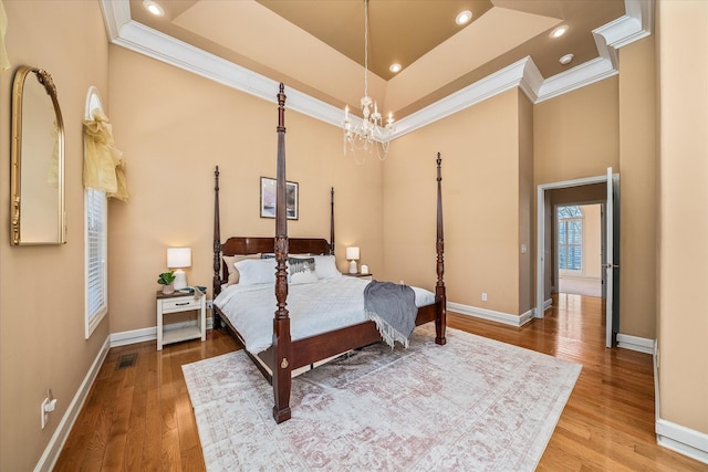 bedroom featuring a tray ceiling, wood finished floors, and baseboards