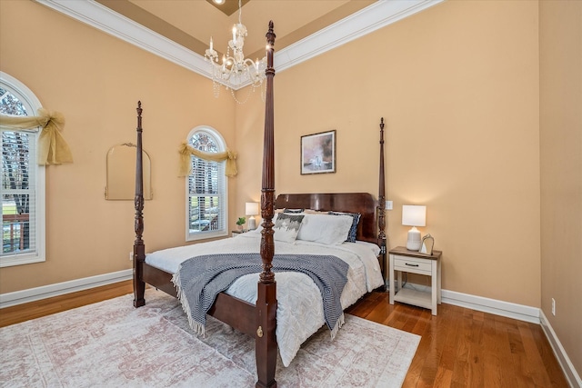 bedroom with baseboards, a chandelier, wood finished floors, and ornamental molding