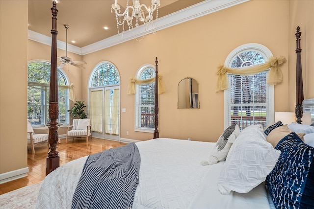 bedroom featuring baseboards, a towering ceiling, ornamental molding, wood finished floors, and an inviting chandelier