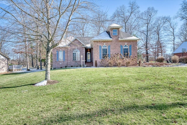 view of front facade with a front yard, brick siding, and roof with shingles