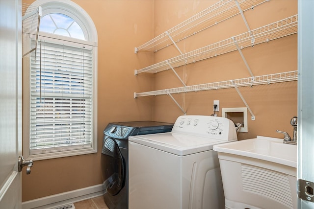 washroom with washing machine and dryer, laundry area, a sink, and baseboards